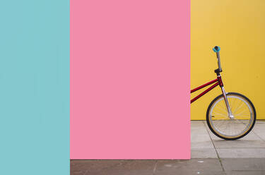 BMX bike standing behind pink wall - JCMF00744