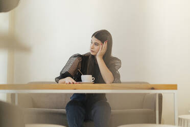 Nachdenkliche junge Frau, die in einem Café sitzt und wegschaut - OCAF00477