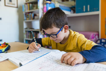 Grundschülerin lernt am Schreibtisch sitzend während des Homeschoolings - MGIF00942