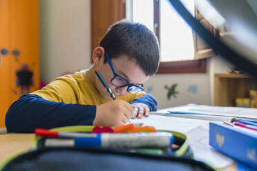 Boy writing in book during homeschooling - MGIF00943