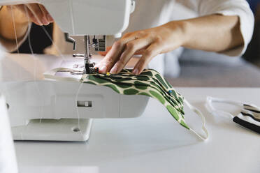 Woman sewing protective face mask at home - MRAF00511