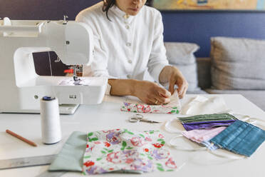 Woman making homemade face mask by sewing machine - MRAF00517