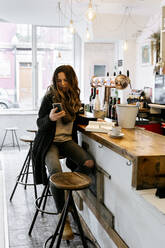 Woman checking smartphoner in coffee shop - MGOF04277