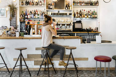 Woman drinking coffee in coffee shop - MGOF04278