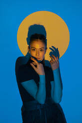 Junge Frau bewegt sich in blauem Licht vor einem gelben Kreis - ALBF01223