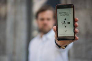 Close-up of man holding smartphone showing distance on display - JOSEF00566