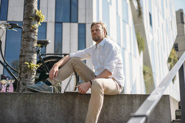 Businessman having a break in the city sitting on a wall - JOSEF00576