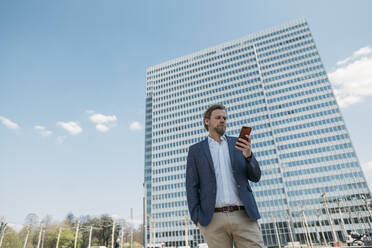 Businessman using smartphone in the city - JOSEF00603