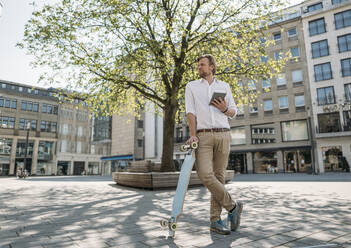 Geschäftsmann mit Tablet und Skateboard in der Stadt - JOSEF00612