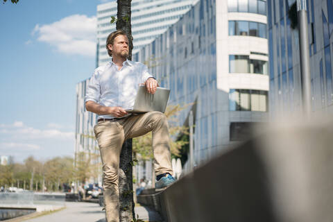 Geschäftsmann mit Laptop in der Stadt, lizenzfreies Stockfoto