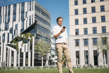 Businessman using smartphone in the city - JOSEF00650