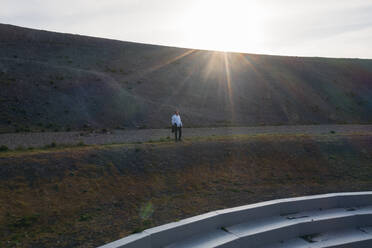 Geschäftsmann vor der BergArena bei Sonnenuntergang - MOEF02868