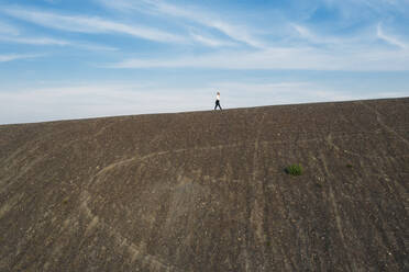 Male professional walking on hill during sunny day - MOEF02876