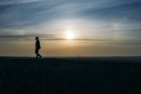 Silhouette Geschäftsmann zu Fuß auf dem Hügel gegen den Himmel bei Sonnenuntergang - MOEF02883