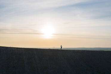 Male professional walking on hill during sunset - MOEF02887