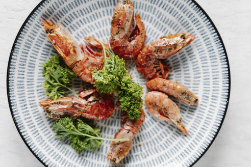 Overhead view of grilled prawns and parsley on plate - JMHMF00045