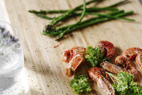 Grilled prawns, parsley and asparagus on wooden cutting board stock photo