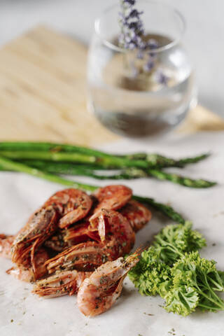 Grilled prawns, parsley and asparagus on wooden cutting board stock photo