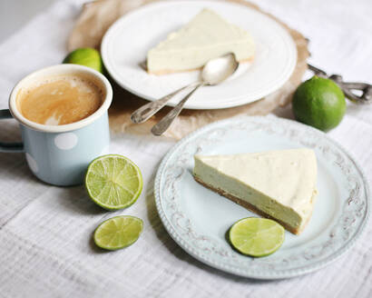 Limetten-Käsekuchen-Scheiben auf Tellern und Kaffee - VBF00045