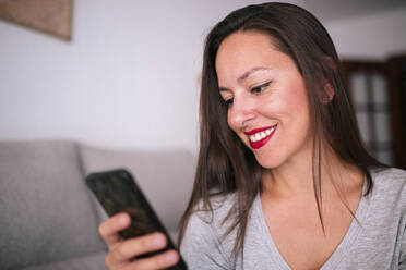 Lächelnde schöne Frau, die zu Hause ein Mobiltelefon benutzt - GRCF00215