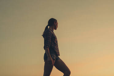 Frau auf einem Bein stehend am Strand bei Sonnenuntergang - DMGF00089