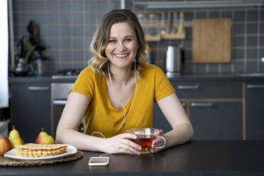 Porträt einer glücklichen Frau beim Musikhören in der Küche zu Hause - VPIF02461