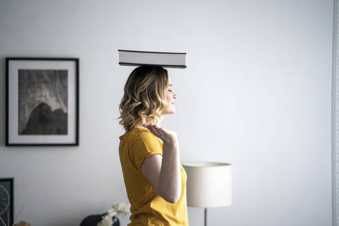 Woman at home balancing a book on her head - VPIF02484