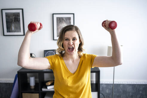 Portrait of screaming woman doing home workout with dumbbells - VPIF02487