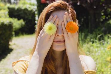 Young woman with flowers on her hands covering her eyes - AFVF06283