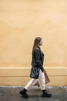 Junge Frau mit Einkaufstüten beim Spaziergang in der Stadt - GRCF00233