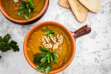 Overhead view of pumpkin soup with walnuts and parsley - GIOF08180