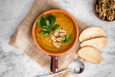 Overhead view of pumpkin soup with walnuts and parsley - GIOF08181