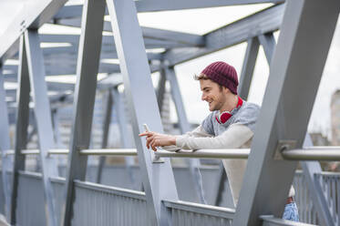 Stylish young man using smartphone on a bridge - DIGF10905