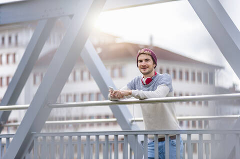 Stylish young man holding smartphone on a bridge stock photo