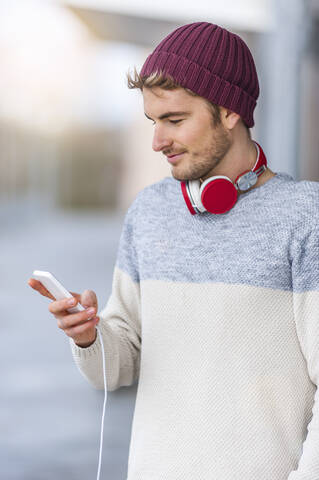 Stylish young man using smartphone outdoors stock photo