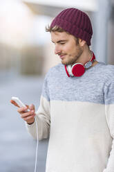 Stilvoller junger Mann benutzt Smartphone im Freien - DIGF10908