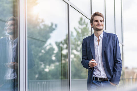 Junger Geschäftsmann mit Smartphone in einem Bürogebäude, lizenzfreies Stockfoto