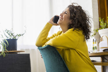 Happy brunette woman talking on the phone in home office - ERRF03755