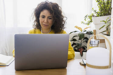 Frau mit Laptop am Schreibtisch im Heimbüro - ERRF03781