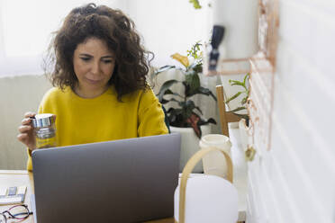 Woman using laptop at desk in home office - ERRF03790