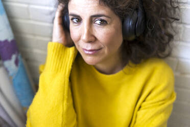 Porträt einer lächelnden Frau, die mit Kopfhörern Musik hört - ERRF03805