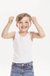 Portrait of little boy clenching fists standing in front of white background - SDAHF00948