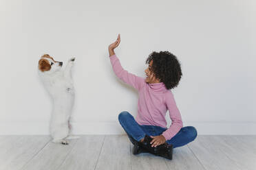 Lächelndes kleines Mädchen, das mit seinem Hund auf dem Boden sitzt - EBBF00004