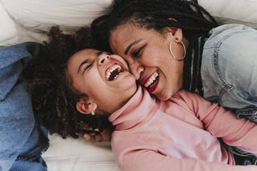 Porträt eines lachenden kleinen Mädchens und ihrer Mutter, die sich gemeinsam zu Hause amüsieren - EBBF00016