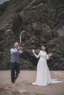 Brautpaar, Mann plantscht mit Champagner am Strand - SNF00212