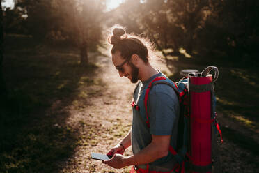 Bärtiger Mann mit Smartphone auf einem Wanderausflug - EBBF00022