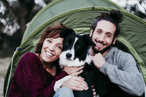 Porträt eines glücklichen Paares mit Hund in einem Zelt - EBBF00054