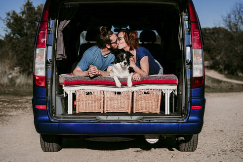 Pärchen mit Hund, das sich im Kofferraum eines Minivans küsst - EBBF00062