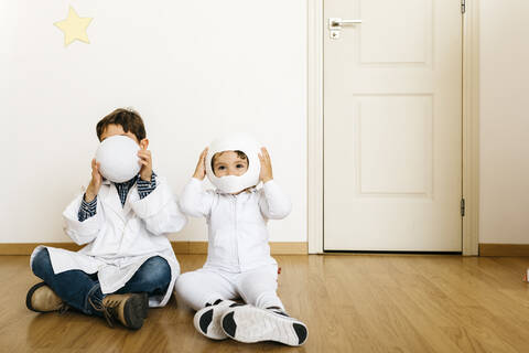 Siblings playing astronaut and researcher at rocket stock photo