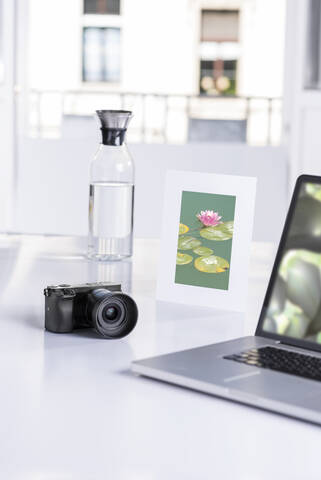 Digital camera, laptop, water carafe and framed picture of water lilies in pond stock photo